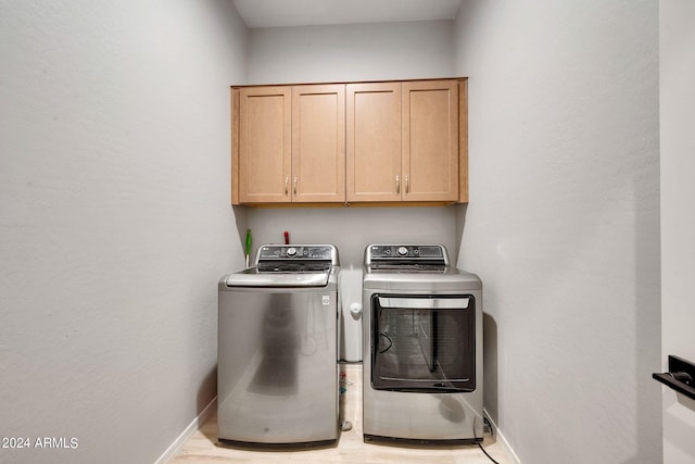 laundry room featuring cabinet space, baseboards, and washing machine and clothes dryer