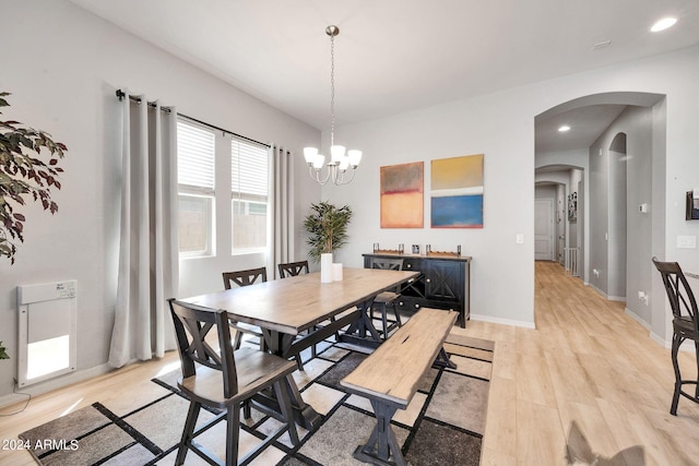 dining space with light wood finished floors, baseboards, arched walkways, a notable chandelier, and recessed lighting