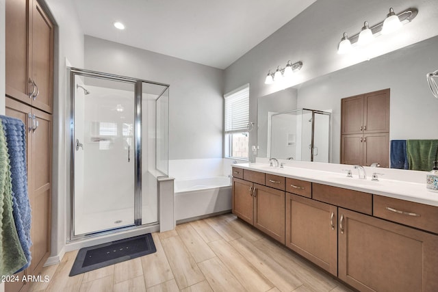 full bathroom with a bath, a stall shower, double vanity, and a sink