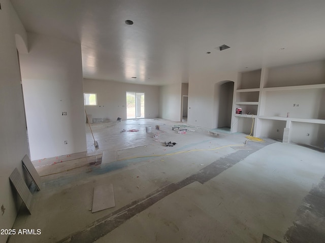 unfurnished living room featuring arched walkways