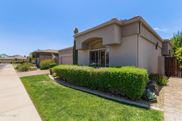 8689 E Krail St, Scottsdale, AZ 85250 - view of home's exterior featuring an attached garage, stucco siding, and a yard