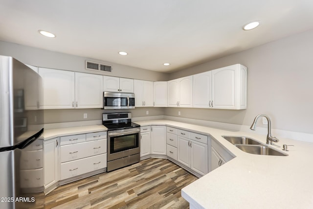 4833 N 63rd Ln, Phoenix, AZ 85033 - kitchen with stainless steel appliances, white cabinets, recessed lighting, light wood-style flooring, and light countertops