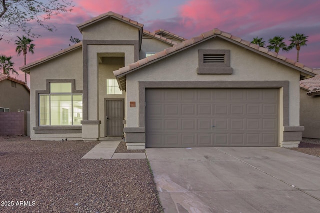 view of front of house featuring a garage, a tile roof, driveway, and stucco siding