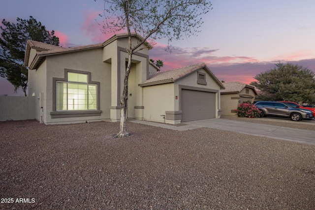 view of front facade with an attached garage, fence, driveway, a tiled roof, and stucco siding