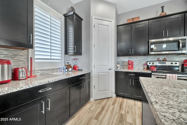 kitchen with light stone counters, backsplash, and appliances with stainless steel finishes