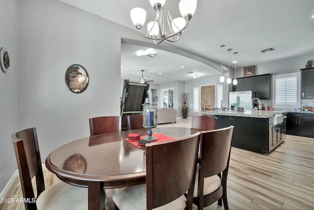 dining area with light hardwood / wood-style flooring and ceiling fan with notable chandelier