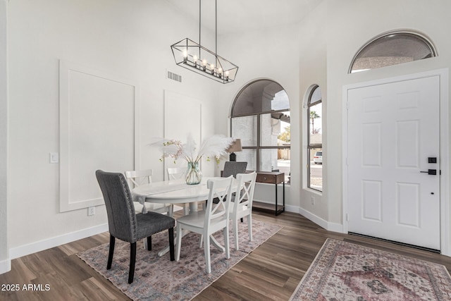 dining area featuring dark hardwood / wood-style flooring, a notable chandelier, and high vaulted ceiling