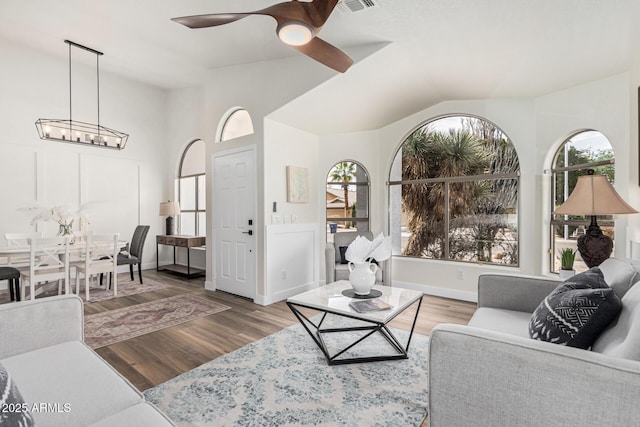 living room featuring hardwood / wood-style flooring, lofted ceiling, and ceiling fan with notable chandelier