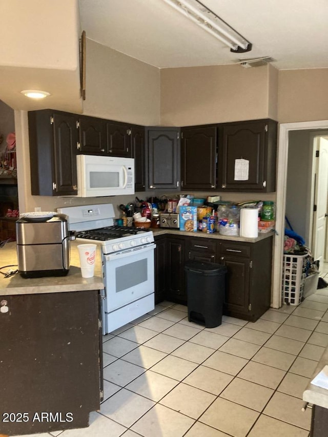 kitchen featuring dark brown cabinets, light tile patterned floors, and white appliances