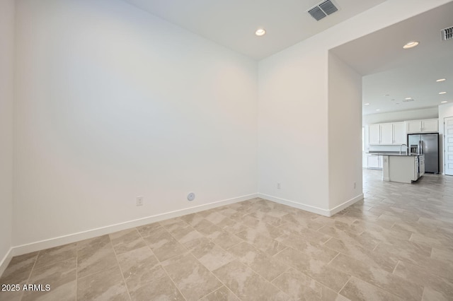 spare room featuring baseboards, a sink, and recessed lighting