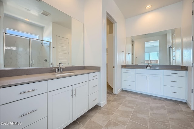 bathroom featuring a shower stall and two vanities
