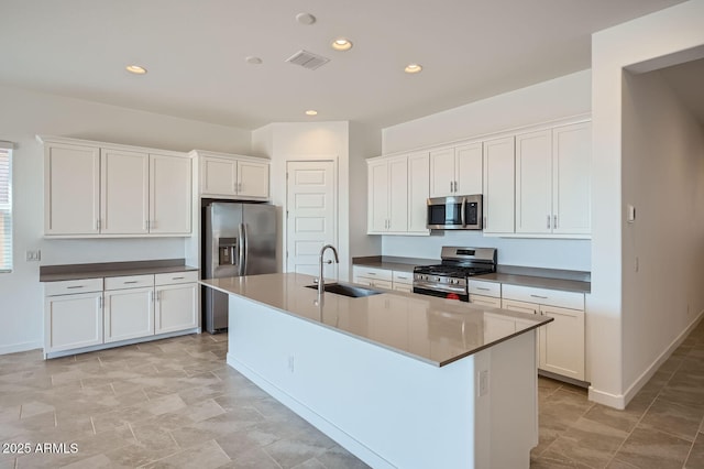 kitchen with appliances with stainless steel finishes, a sink, white cabinets, a center island with sink, and recessed lighting