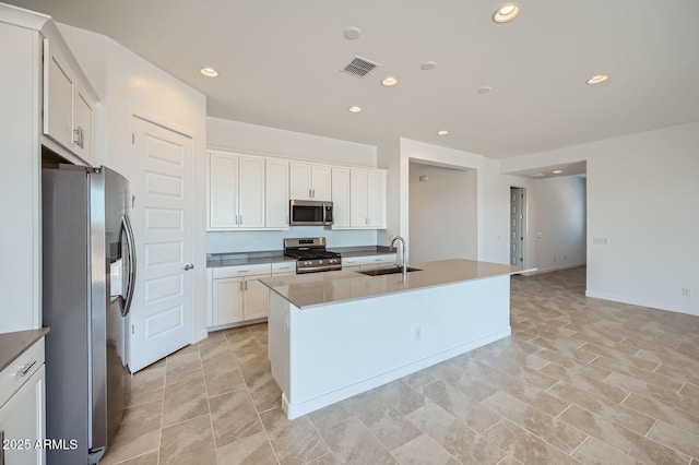 kitchen featuring stainless steel appliances, a sink, recessed lighting, white cabinets, and a center island with sink