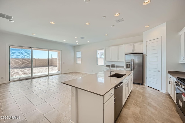 kitchen featuring appliances with stainless steel finishes, a sink, baseboards, white cabinets, and recessed lighting