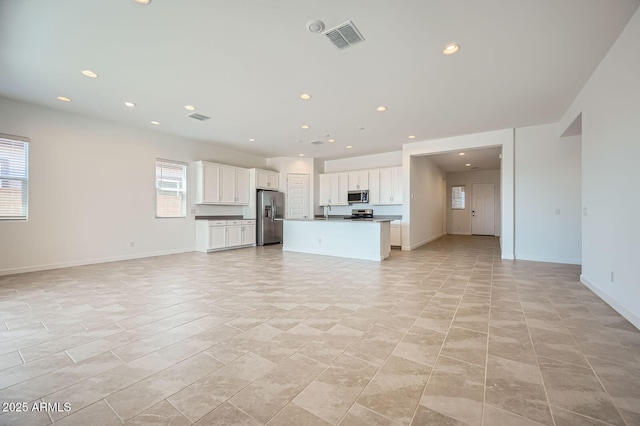 unfurnished living room featuring recessed lighting, a sink, and baseboards
