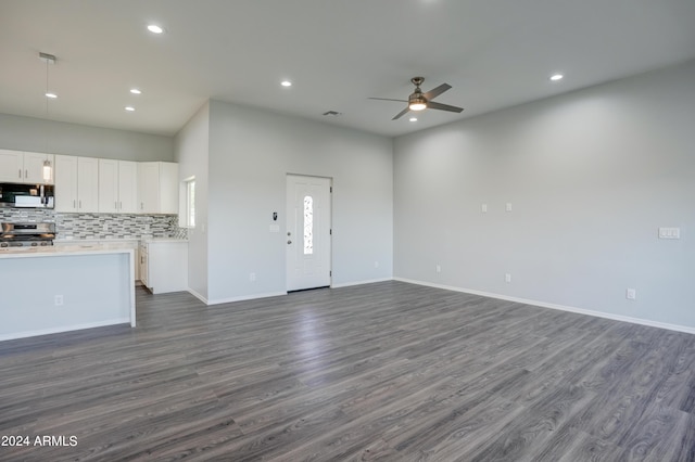 unfurnished living room featuring dark wood-type flooring and ceiling fan