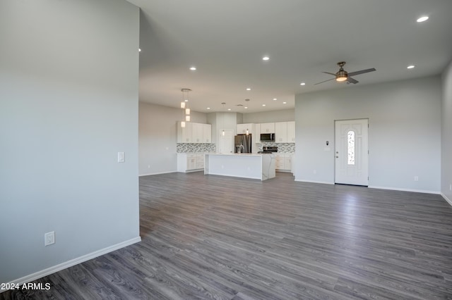 unfurnished living room featuring ceiling fan and dark hardwood / wood-style floors