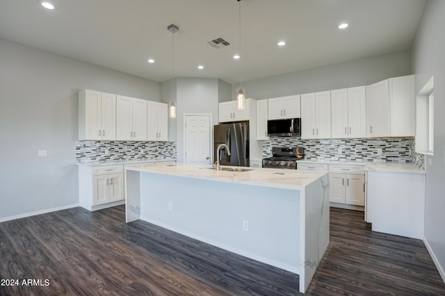 kitchen featuring pendant lighting, sink, appliances with stainless steel finishes, white cabinetry, and an island with sink