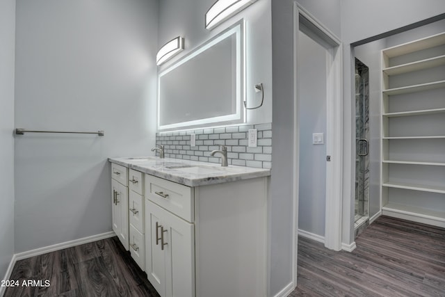 bathroom with hardwood / wood-style flooring, vanity, walk in shower, and decorative backsplash