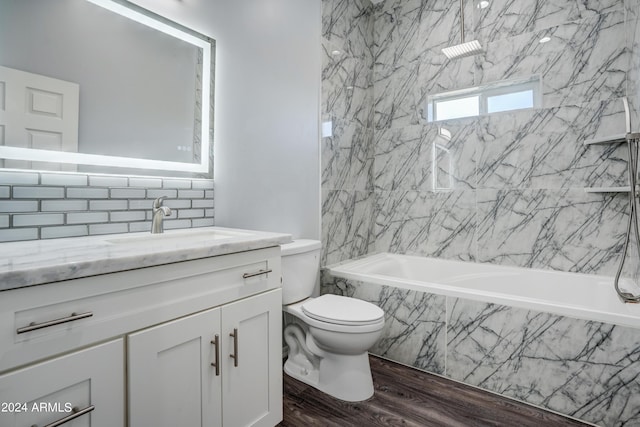 full bathroom with decorative backsplash, tiled shower / bath combo, vanity, hardwood / wood-style flooring, and toilet