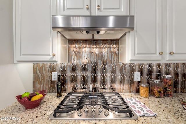 5407 S Tatum Ln, Gilbert, AZ 85298 - kitchen view of stainless steel gas stovetop, tasteful backsplash, exhaust hood, white cabinets, and light stone countertops