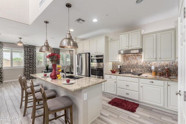 5407 S Tatum Ln, Gilbert, AZ 85298 - kitchen featuring stainless steel appliances, a sink, under cabinet range hood, tasteful backsplash, and white cabinets