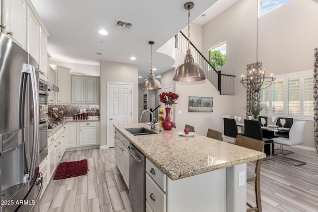 5407 S Tatum Ln, Gilbert, AZ 85298 - kitchen featuring stainless steel appliances, a sink, a center island with sink, light wood-style floors, and a chandelier
