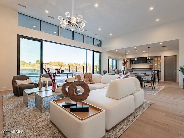 living room with light hardwood / wood-style floors, a high ceiling, and an inviting chandelier