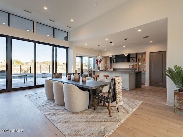 dining space featuring light hardwood / wood-style flooring and a towering ceiling