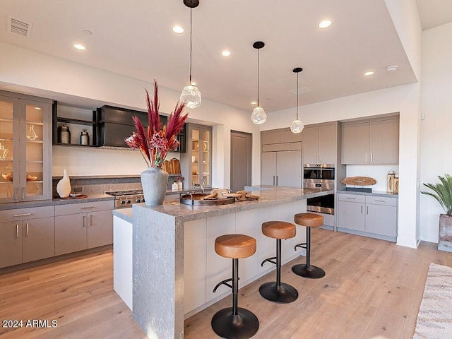 kitchen with paneled refrigerator, a center island, gray cabinets, and a breakfast bar area