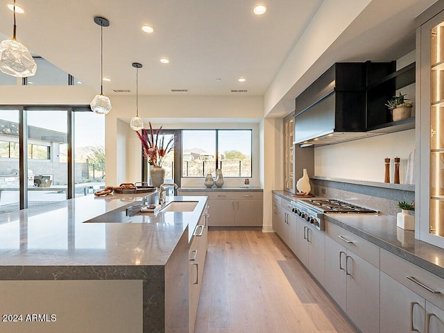 kitchen with sink, light wood-type flooring, hanging light fixtures, and a large island