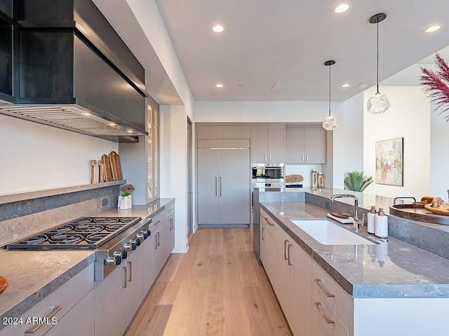 kitchen featuring sink, paneled built in refrigerator, gray cabinetry, wall chimney exhaust hood, and stainless steel gas cooktop