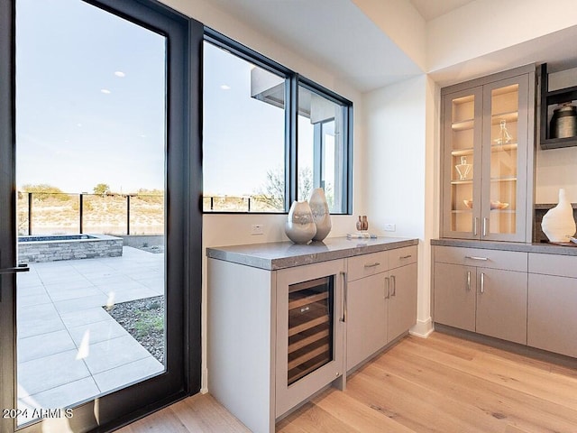 bar featuring wine cooler and light hardwood / wood-style flooring