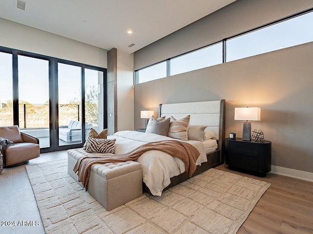 bedroom featuring multiple windows, light hardwood / wood-style flooring, and access to outside