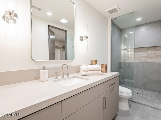 bathroom with vanity, tiled shower, toilet, and tile patterned floors