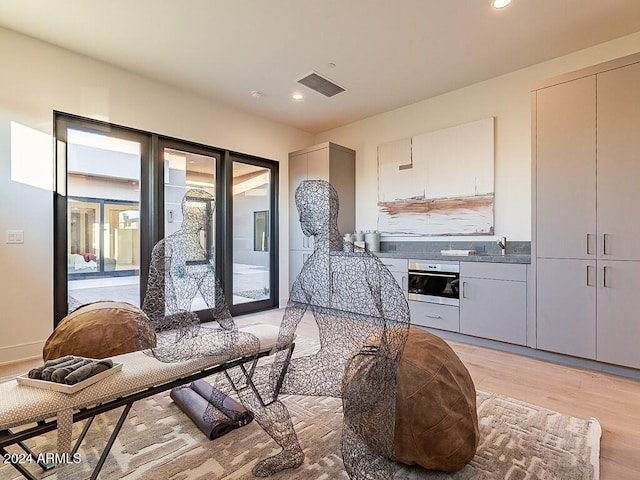 kitchen with gray cabinets, oven, and light hardwood / wood-style flooring