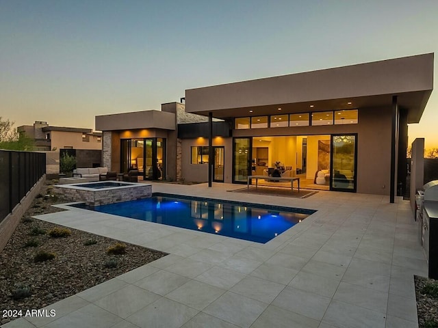 back house at dusk featuring a patio and a swimming pool with hot tub