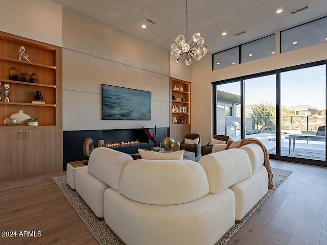 living room with hardwood / wood-style flooring, built in shelves, and a notable chandelier