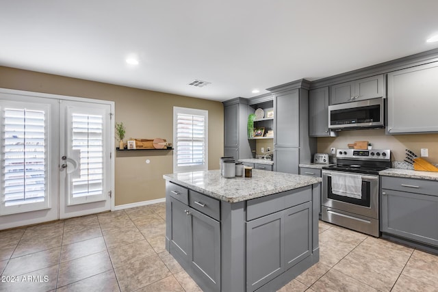 kitchen with gray cabinets, light tile patterned floors, and stainless steel appliances