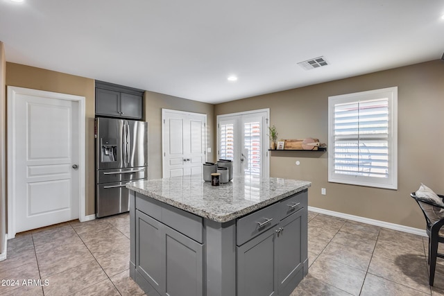 kitchen with stainless steel fridge, a kitchen island, plenty of natural light, and gray cabinetry