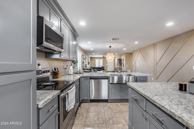 kitchen featuring stainless steel appliances, kitchen peninsula, pendant lighting, gray cabinets, and light tile patterned floors