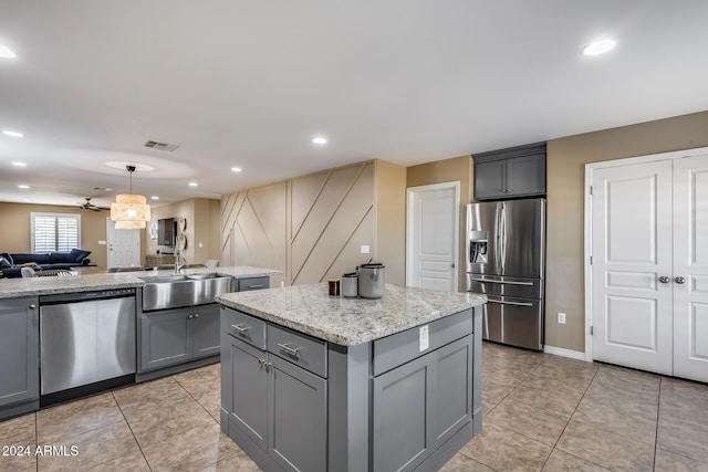 kitchen with gray cabinetry, ceiling fan, appliances with stainless steel finishes, decorative light fixtures, and a kitchen island