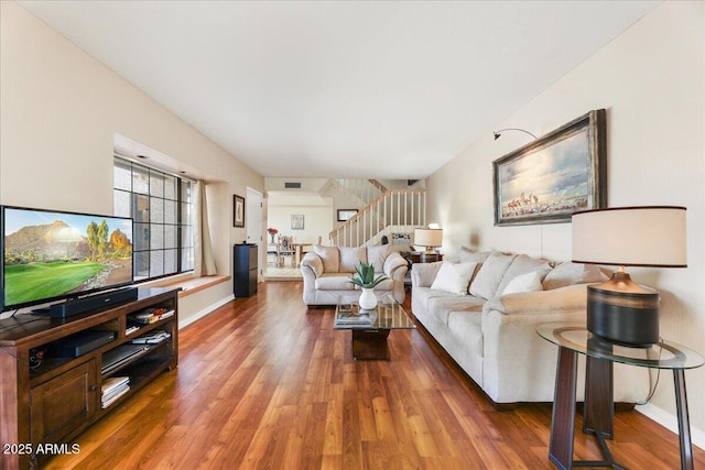 living room featuring visible vents, baseboards, wood finished floors, and stairs