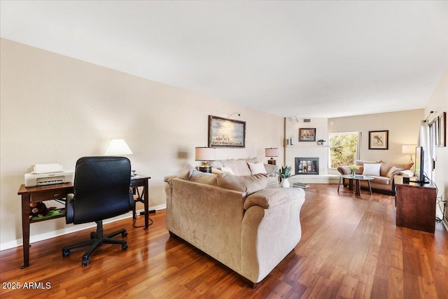 living room with a fireplace, wood finished floors, and baseboards