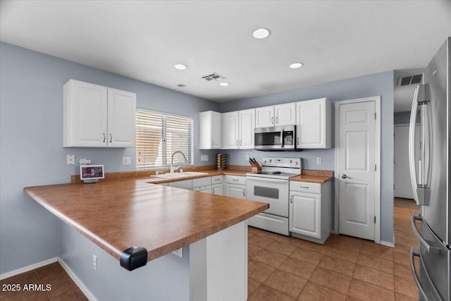 kitchen featuring white cabinetry, sink, stainless steel appliances, and kitchen peninsula