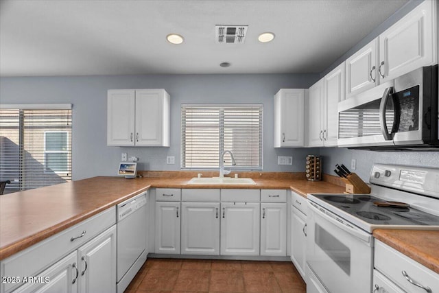 kitchen featuring white cabinetry, sink, white appliances, and a healthy amount of sunlight