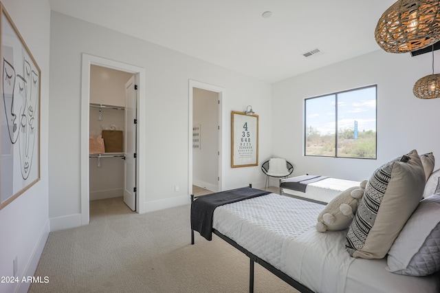 bedroom featuring a walk in closet, light colored carpet, visible vents, and baseboards