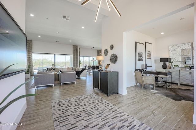 living area featuring recessed lighting, wood finish floors, a towering ceiling, baseboards, and visible vents