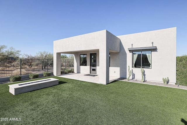 back of property featuring a patio, a lawn, fence, and stucco siding