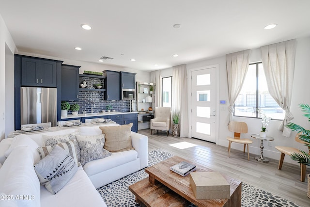 living area featuring baseboards, recessed lighting, visible vents, and light wood-style floors